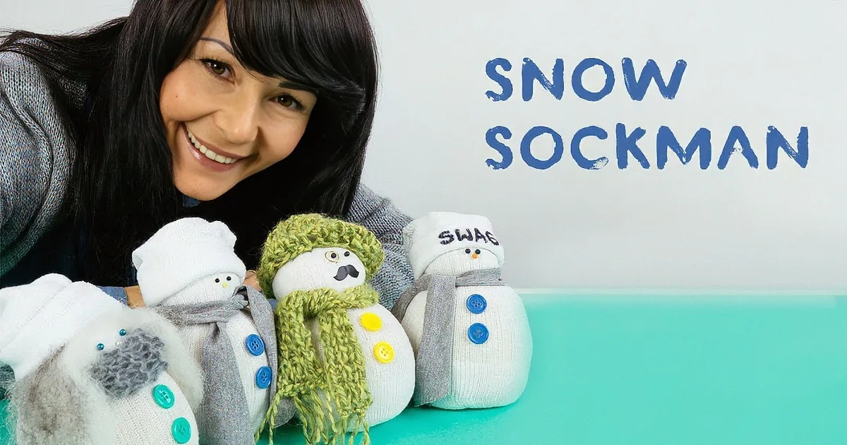 A woman smiles as she shows off her creative snowman socks on a teal surface.