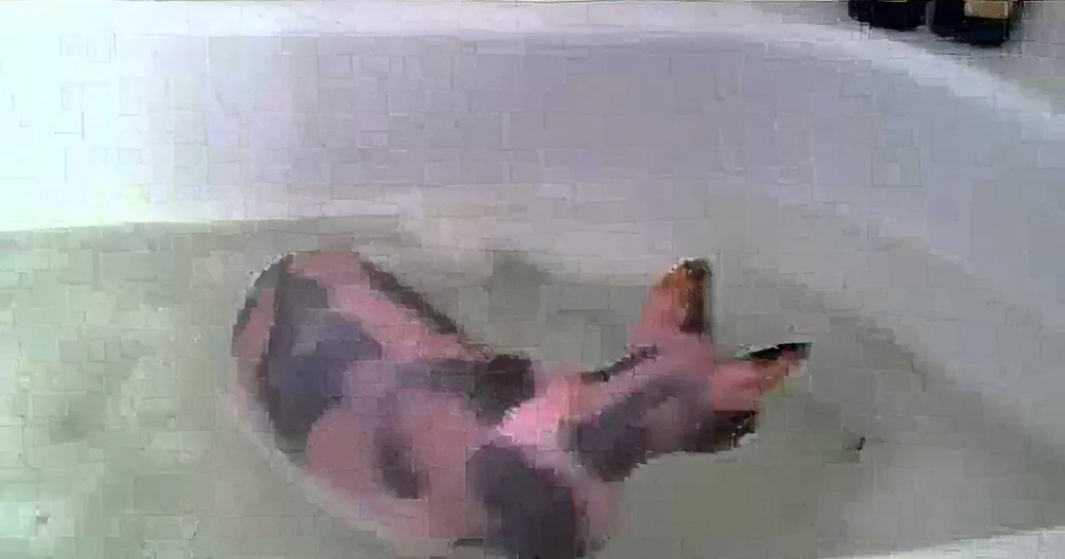 A pink and black spotted fish swims in a white container filled with water.