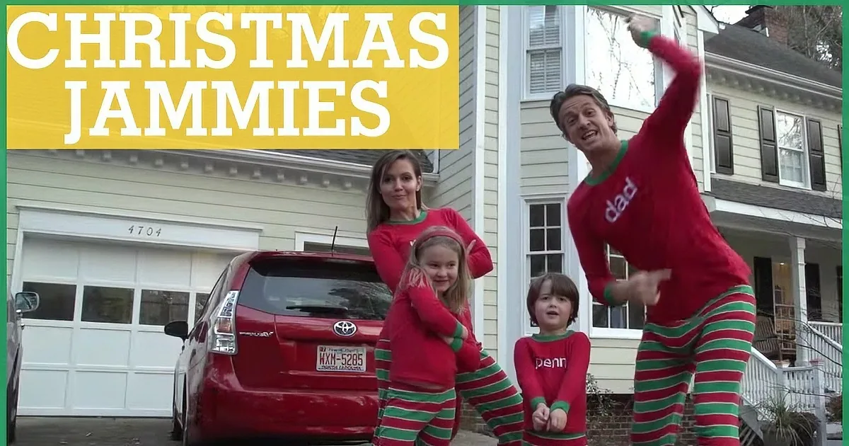 A family in red and green striped pajamas dances in front of a house, celebrating Christmas.