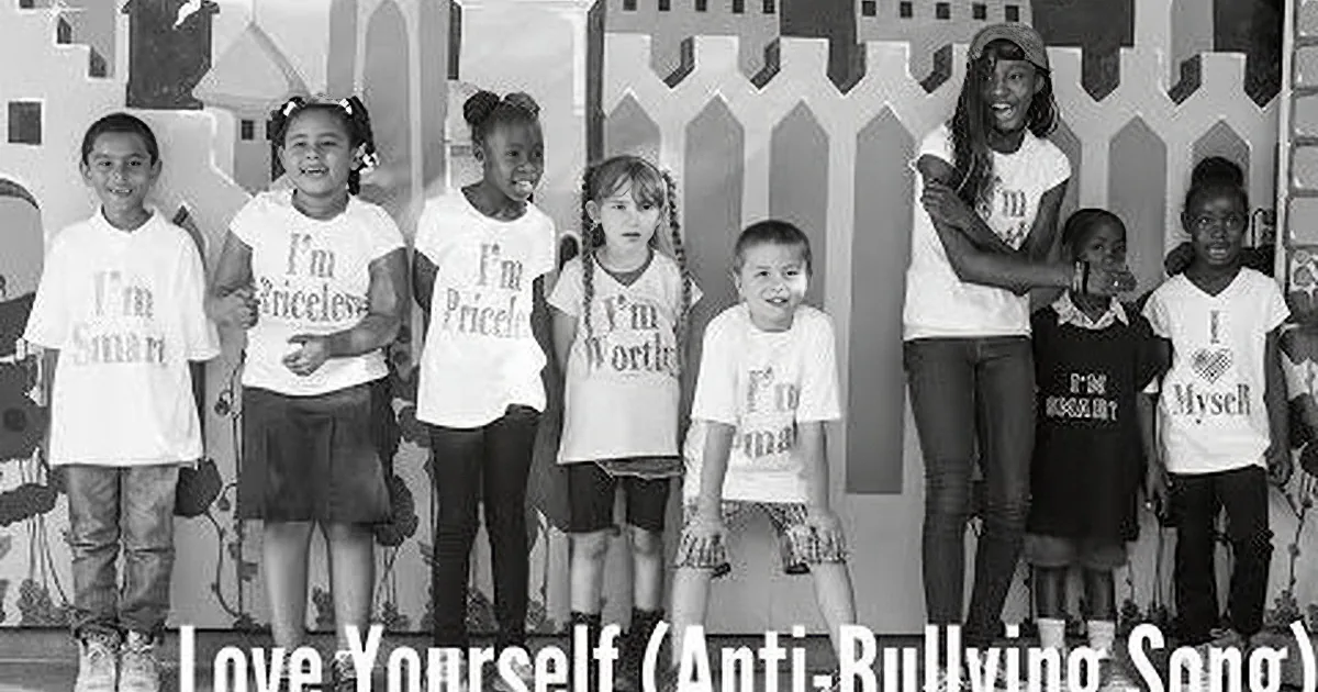 Children in white shirts with affirmations stand in front of a fence, promoting self-love and positivity.