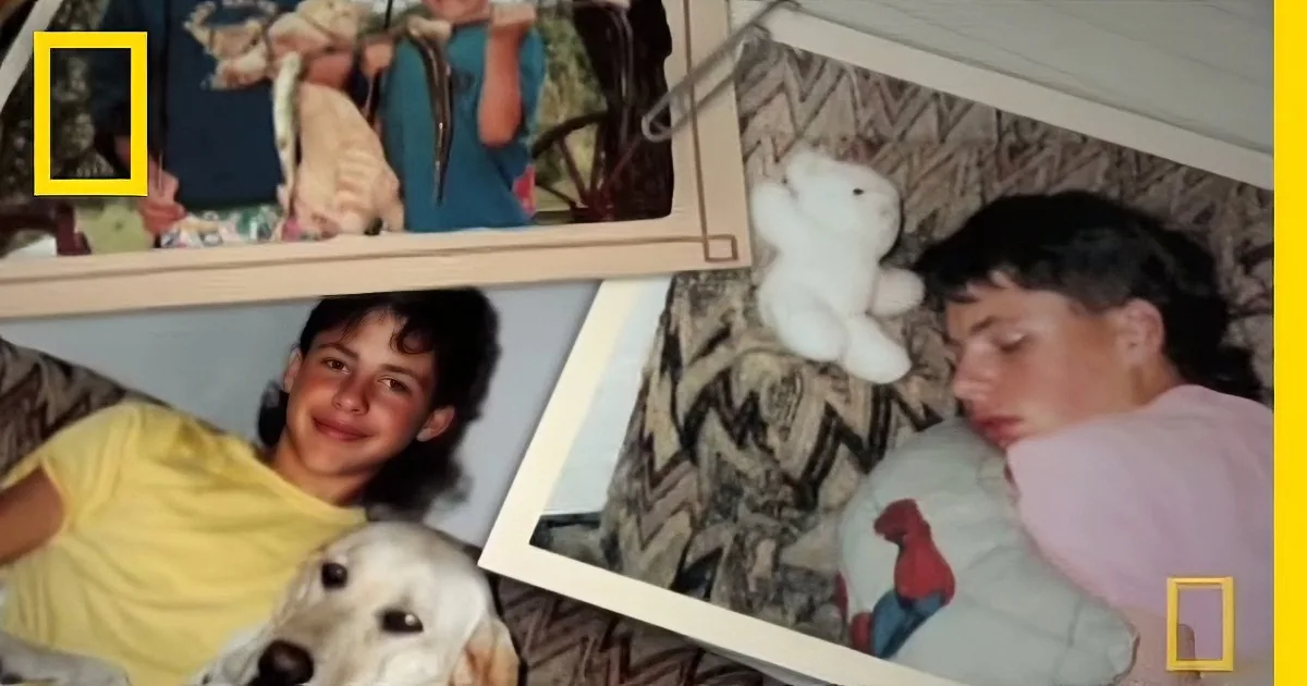A young boy holds a stuffed animal, surrounded by family photos and a dog.