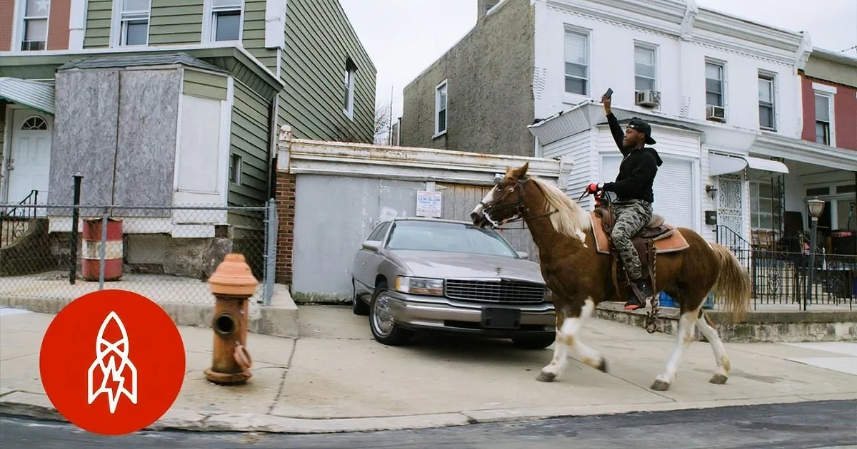 A person rides a horse on a city sidewalk, holding a phone, with buildings and a car in the background.