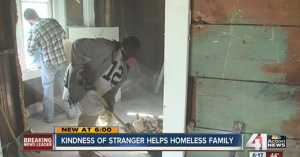 A man in a gray hoodie works inside a house, surrounded by construction debris.