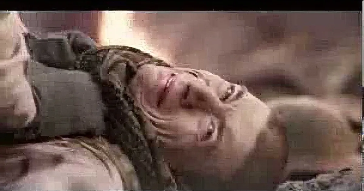 A person with long hair, wearing a dark top, is lying down, appearing distressed or injured.