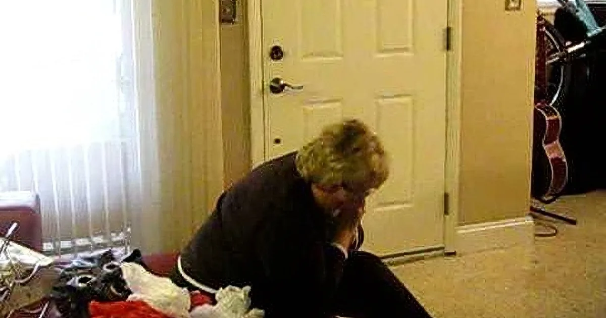A person is bending over, surrounded by scattered items on the floor near a door.