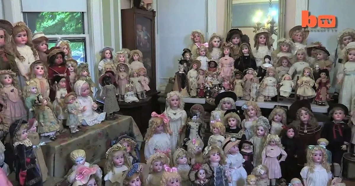 A collection of vintage dolls with various hairstyles and outfits is displayed in a room.