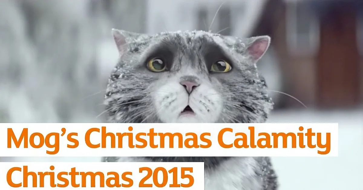A gray cat with snow on its fur, looking up, with text overlay mentioning "Moa's Christmas Calamity" and "Christmas 2015."