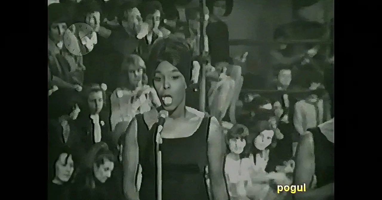 A woman sings into a microphone surrounded by a crowd in a black-and-white image.