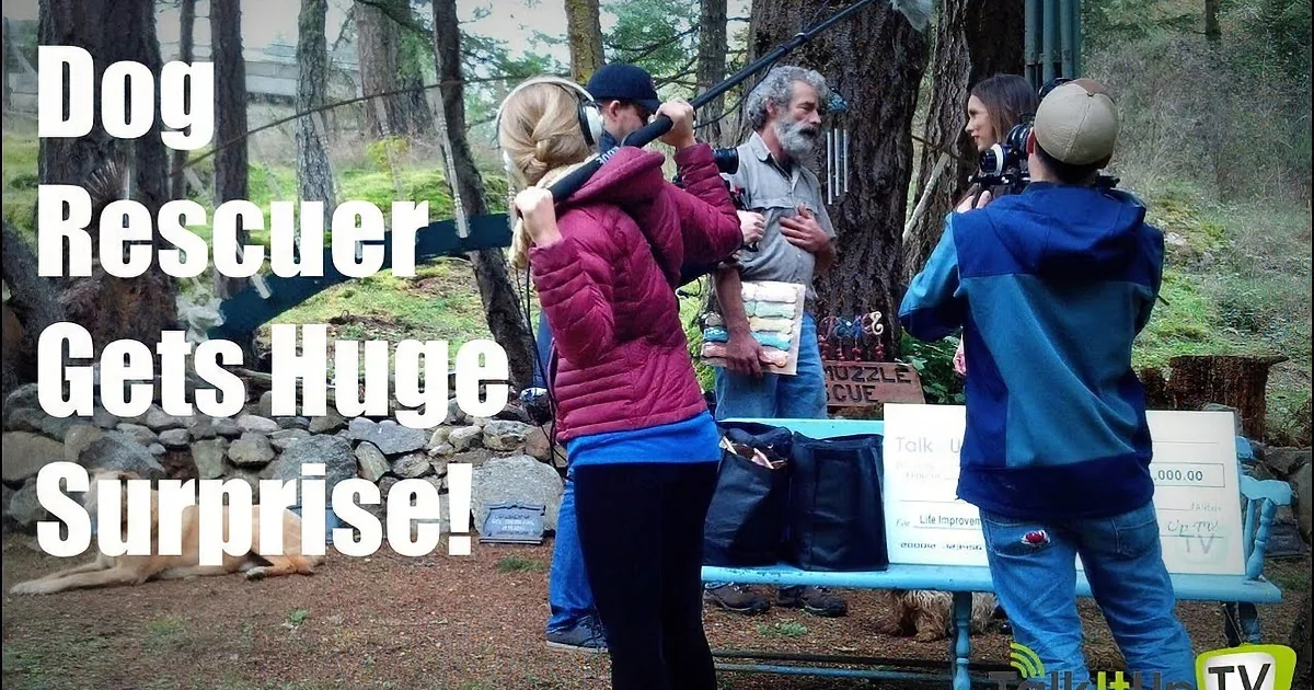 A dog rescuer is being interviewed by a TV crew in a forest setting.