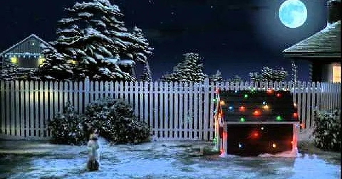 A child stands in a snowy yard under a full moon, surrounded by Christmas lights and a white picket fence.