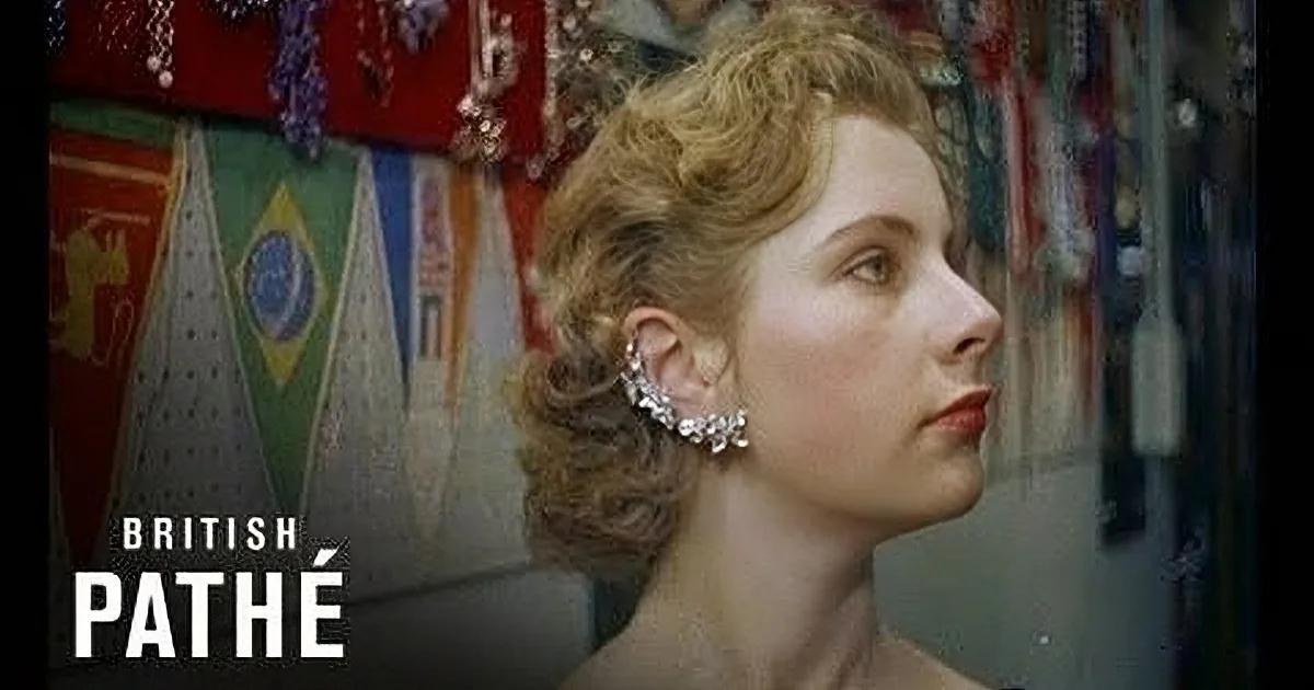 A woman with curly hair and a pearl earring is looking up, surrounded by colorful flags.