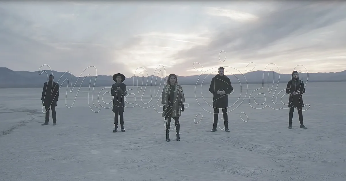 Five people stand in a line on a vast, snowy landscape under a cloudy sky.