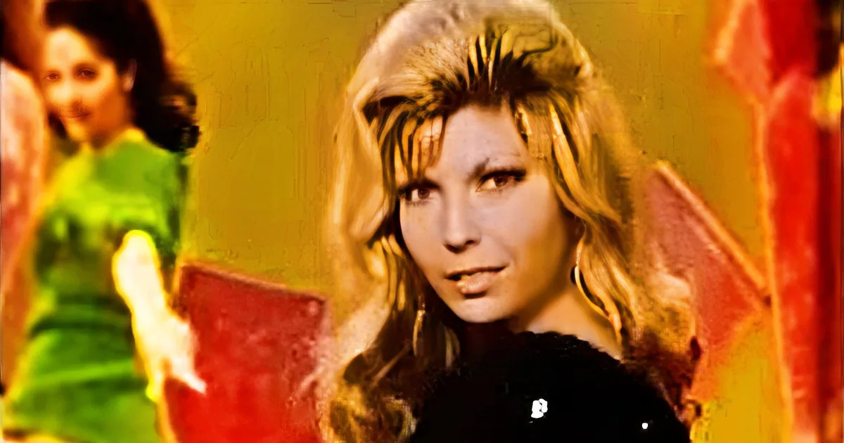 A woman with long, wavy blonde hair and a black top is in the foreground, while another woman in a green dress is in the...