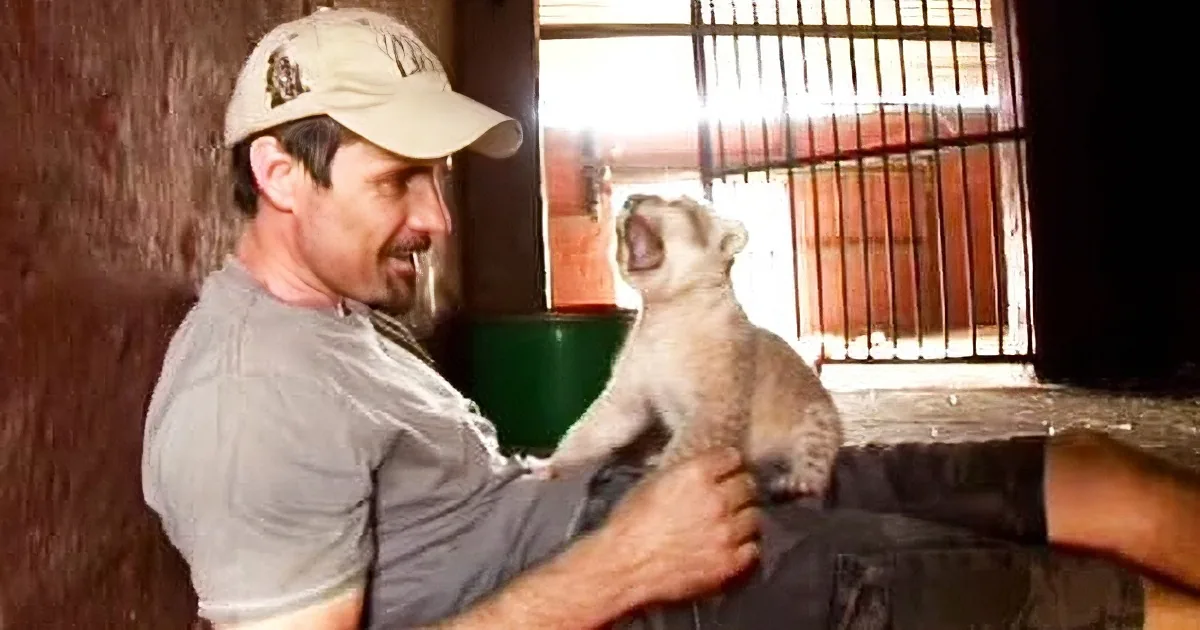 A man in a cap interacts with a large dog in a rustic setting, showing affection and trust.