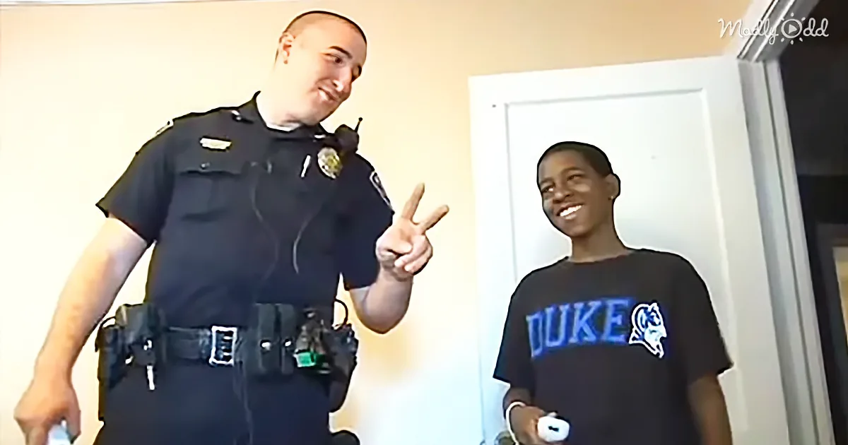 A police officer in uniform gives a peace sign next to a boy in a Duke shirt.