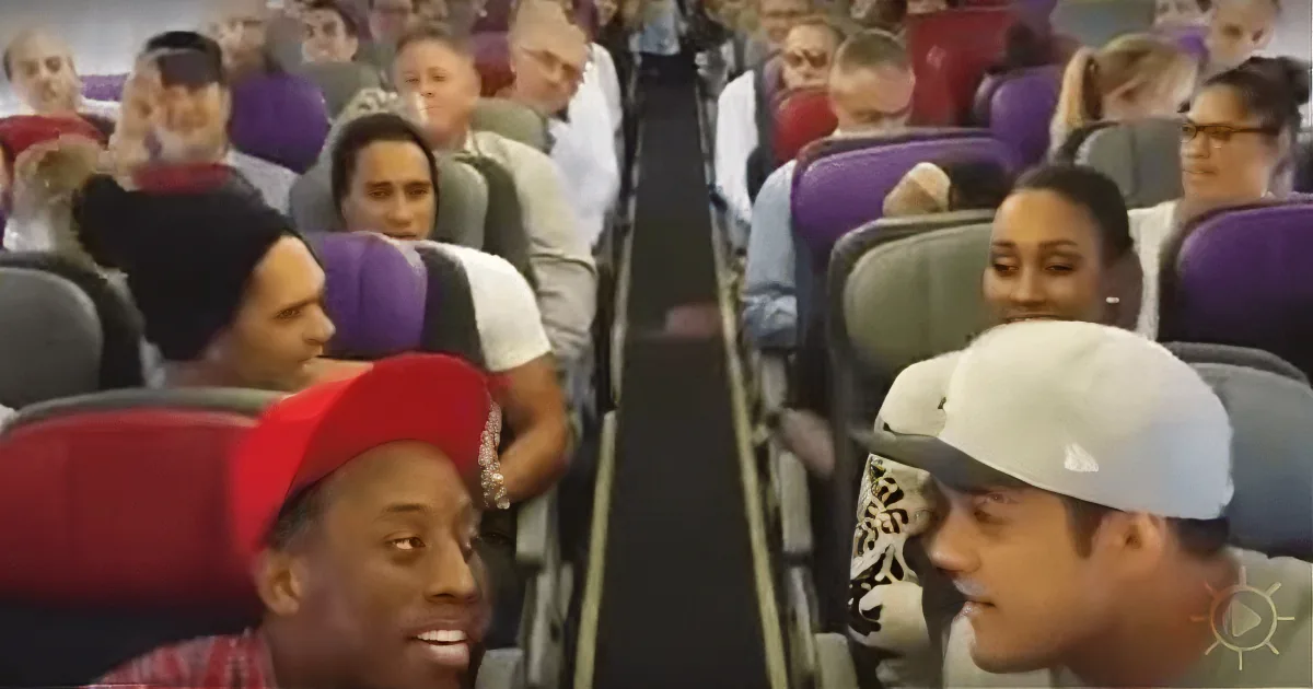 Two individuals in a crowded airplane, one wearing a red cap, the other a white cap, both looking at each other.