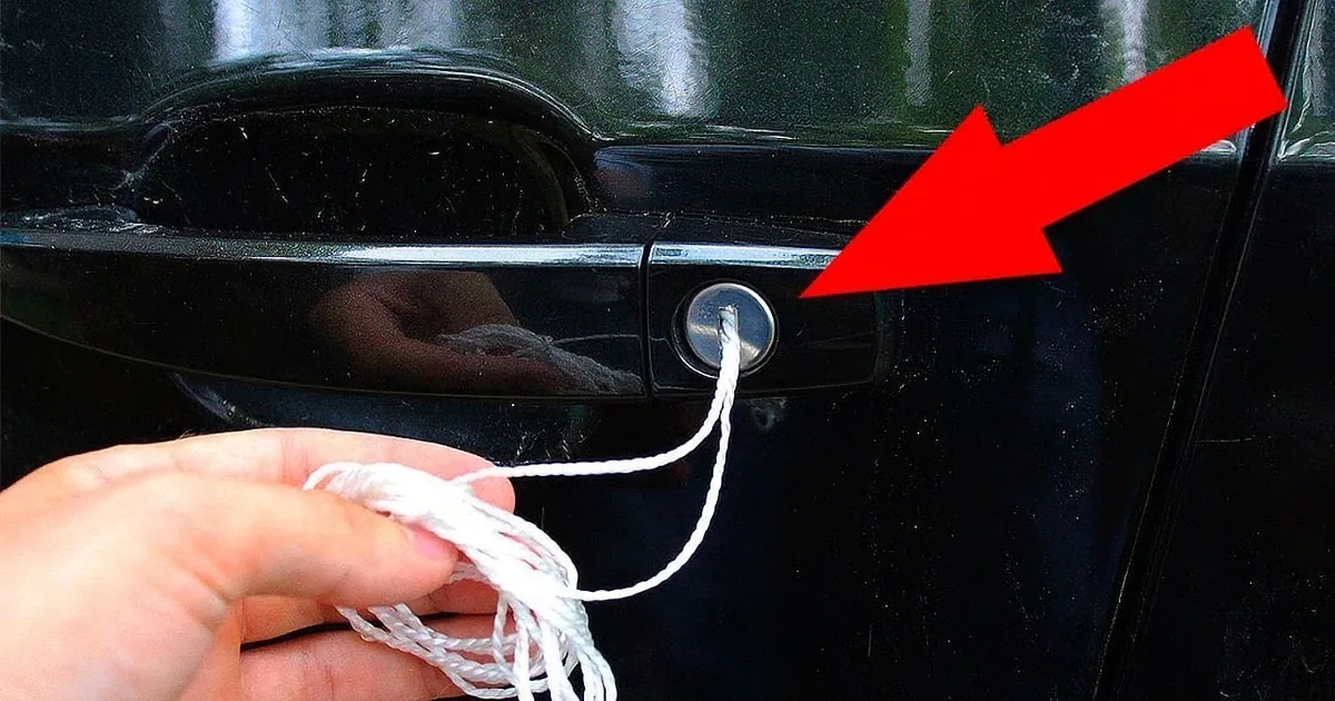 A hand holds white string near a car door lock with a red arrow pointing to it.
