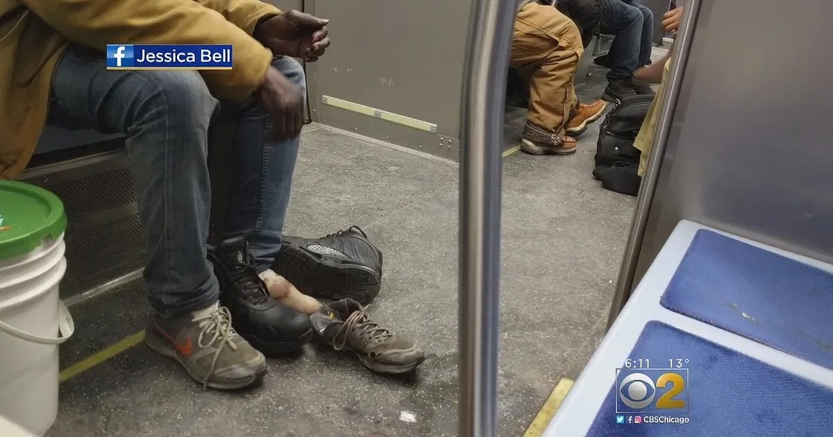 A person's leg is visible through a gap in the subway seats, with shoes and a bucket nearby.