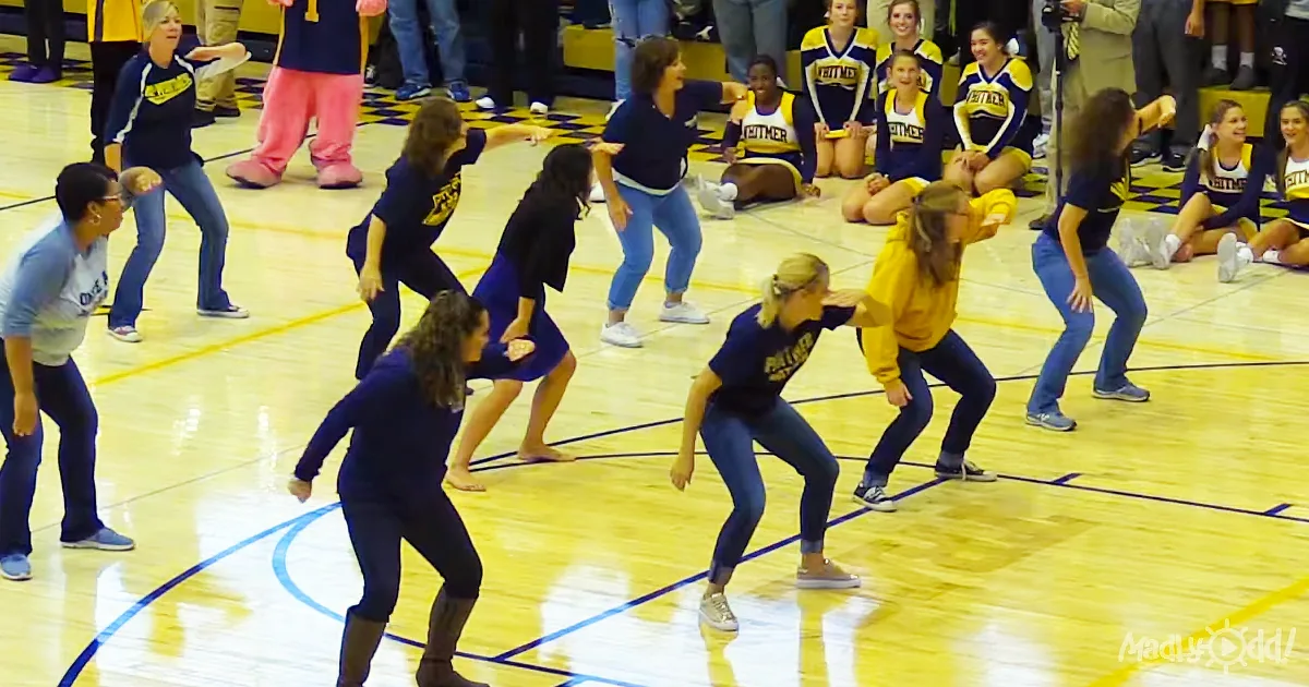 Women in blue and yellow outfits are dancing on a basketball court.
