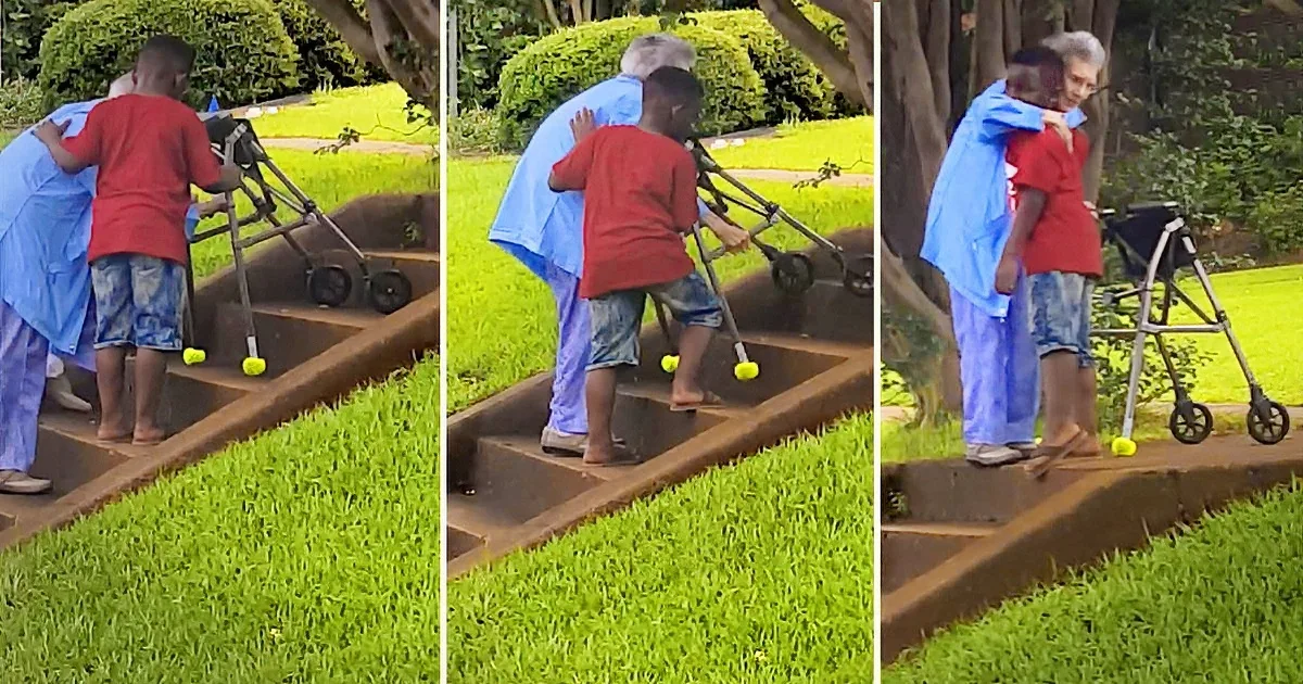 A young boy helps an elderly woman with a walker up a set of stairs.