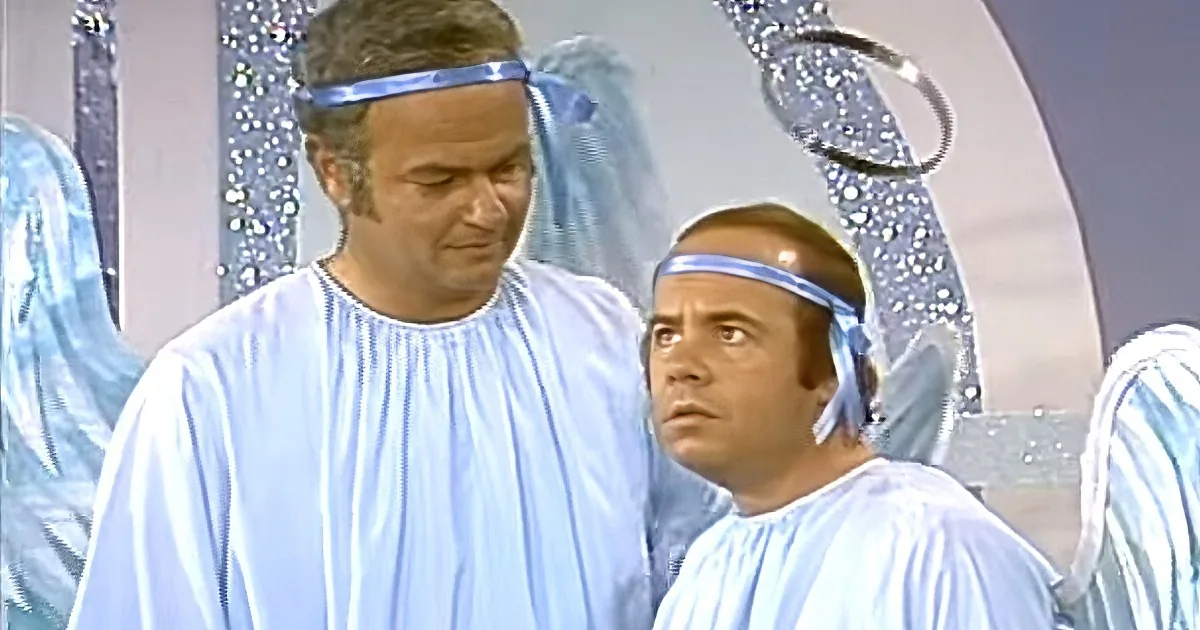 Two men in white robes with blue headbands stand in a room with sparkling decorations.