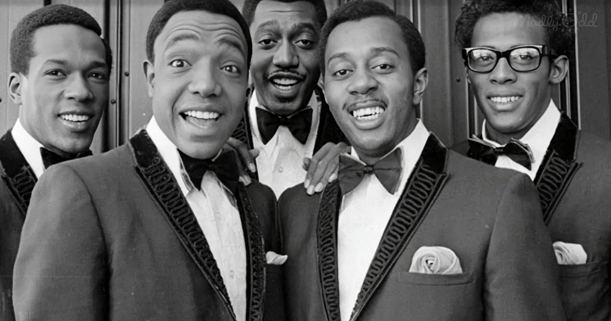 A group of five men in suits and bow ties, smiling and posing together.