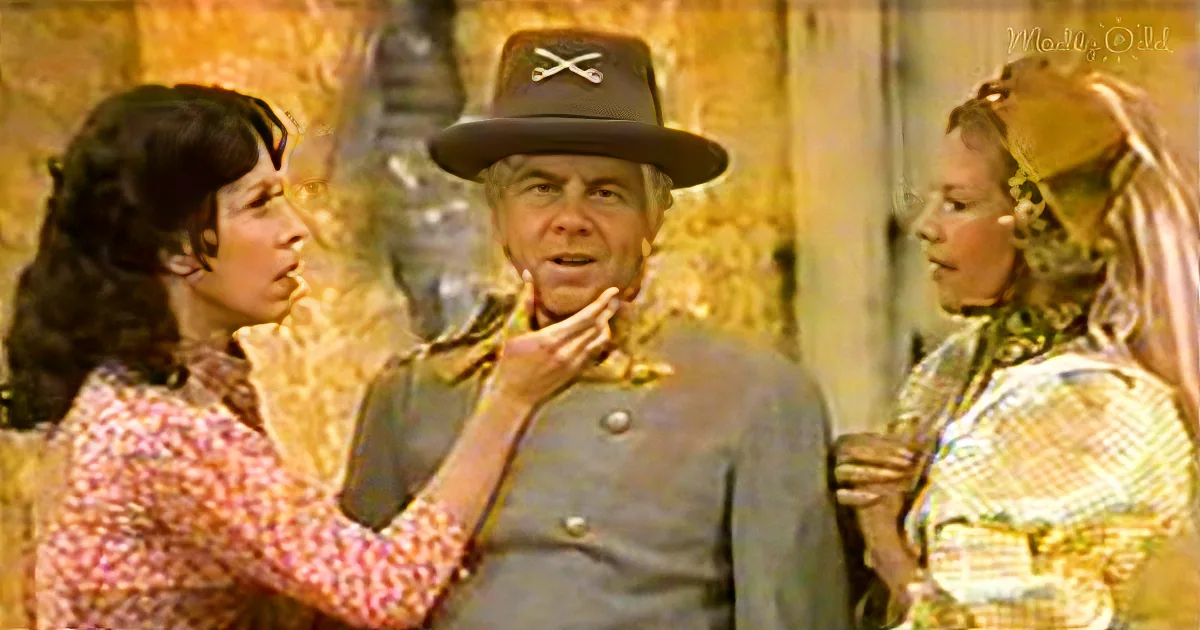 A man in a Confederate uniform is being touched on the face by two women in period attire.