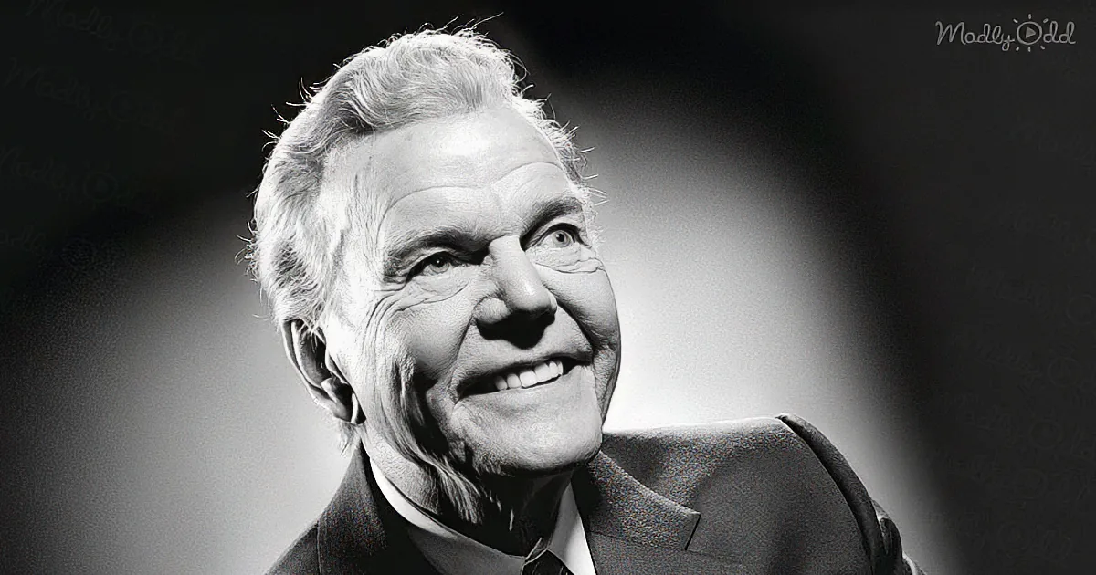 A smiling older man in a suit, looking upwards, with a black-and-white filter and "Madly Odd" watermark.
