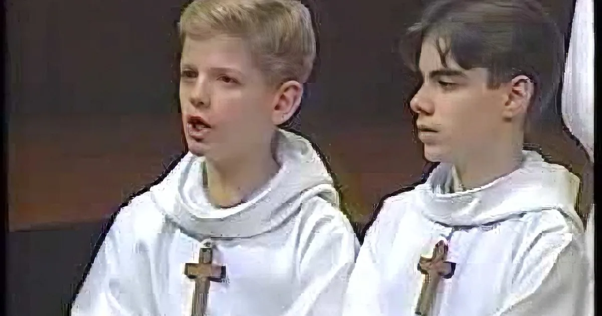 Two young boys in white robes with crosses, possibly participating in a religious ceremony.