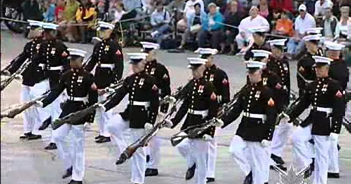 Marines in formal attire march in formation during a parade.
