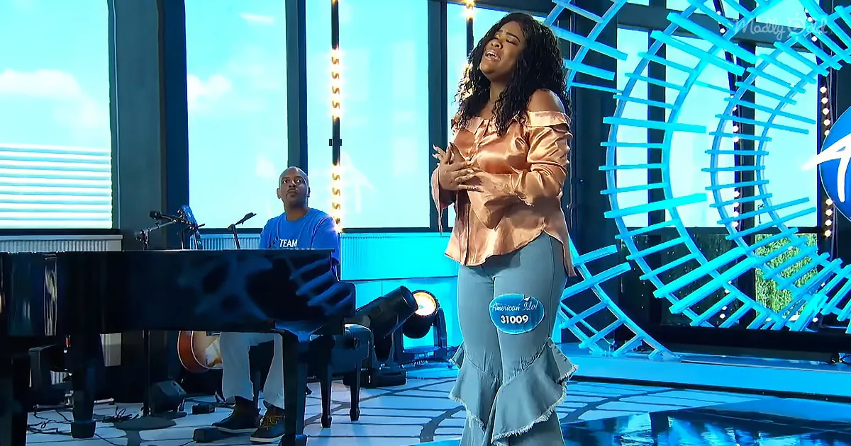 A woman in a pink top and blue pants sings passionately on stage, accompanied by a pianist.