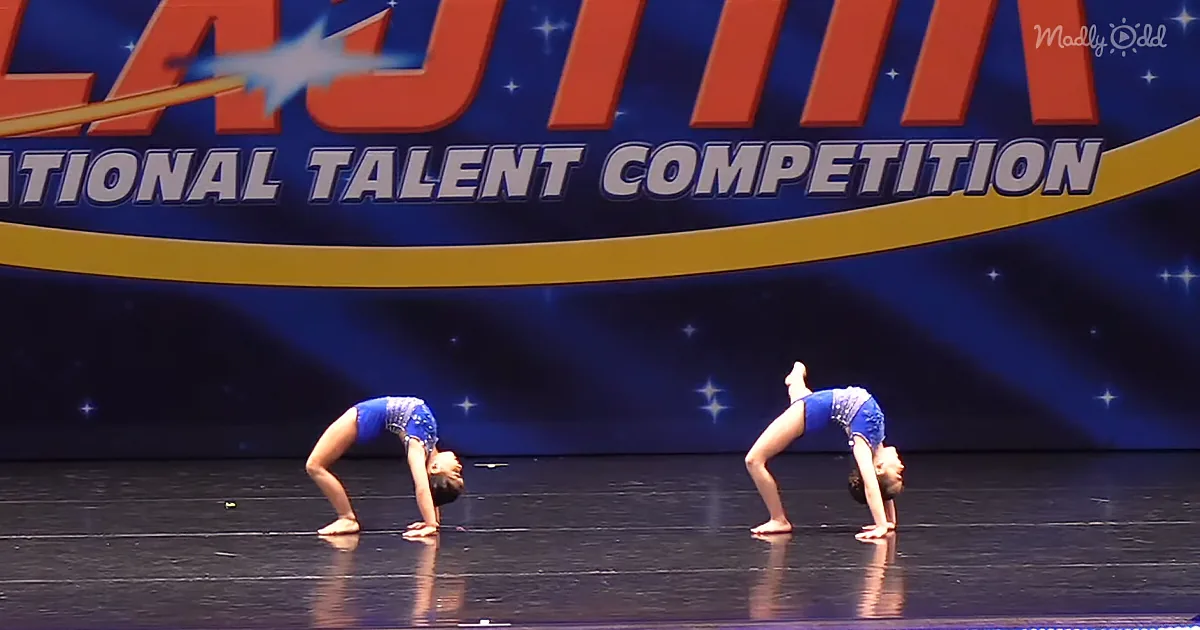 Two performers in blue outfits execute a bridge pose on a stage with a "National Talent Competition" backdrop.