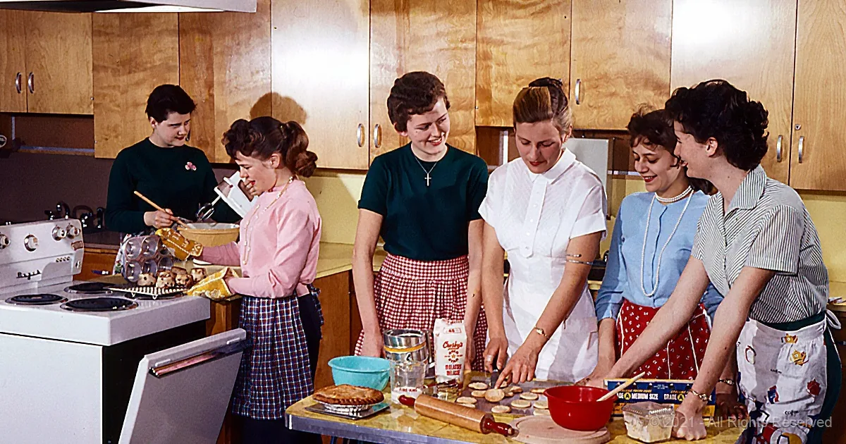Women in a kitchen preparing food, smiling and working together.