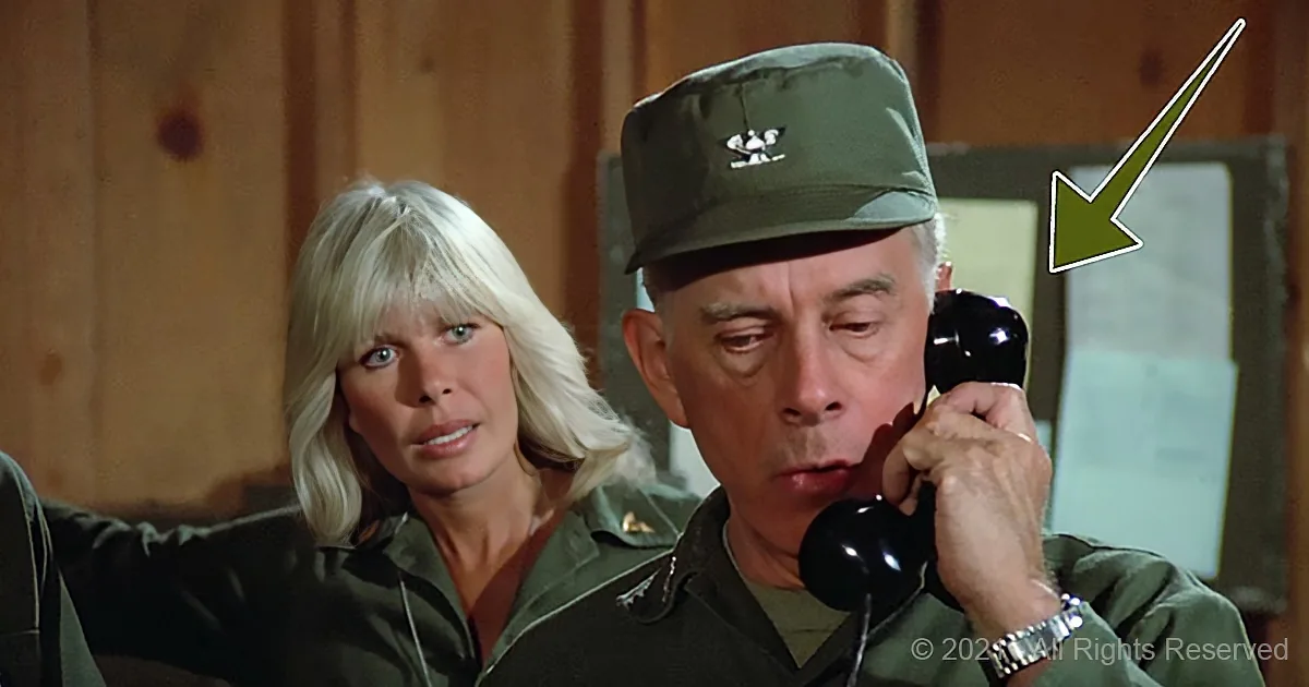 A man in a military uniform is talking on a phone, with a woman in a green jacket standing beside him.