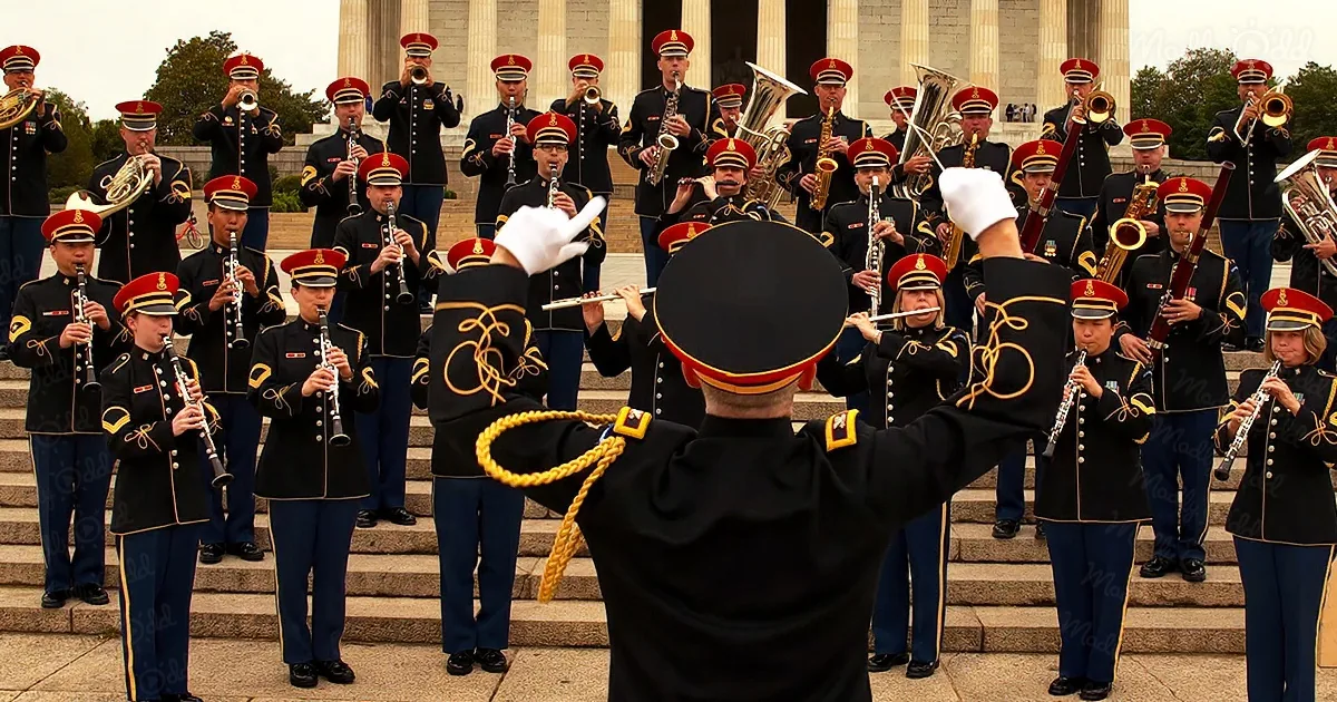 A Marine band conductor leads a uniformed ensemble playing instruments on steps.