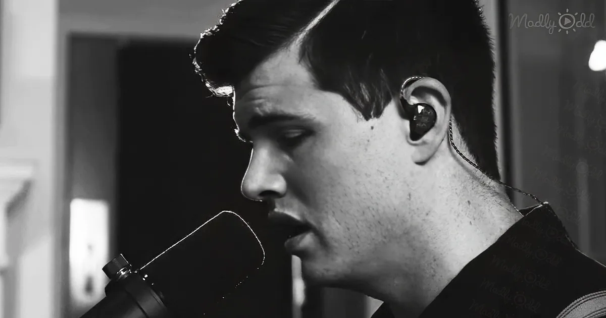 A man with earphones sings into a microphone, captured in a black-and-white close-up.