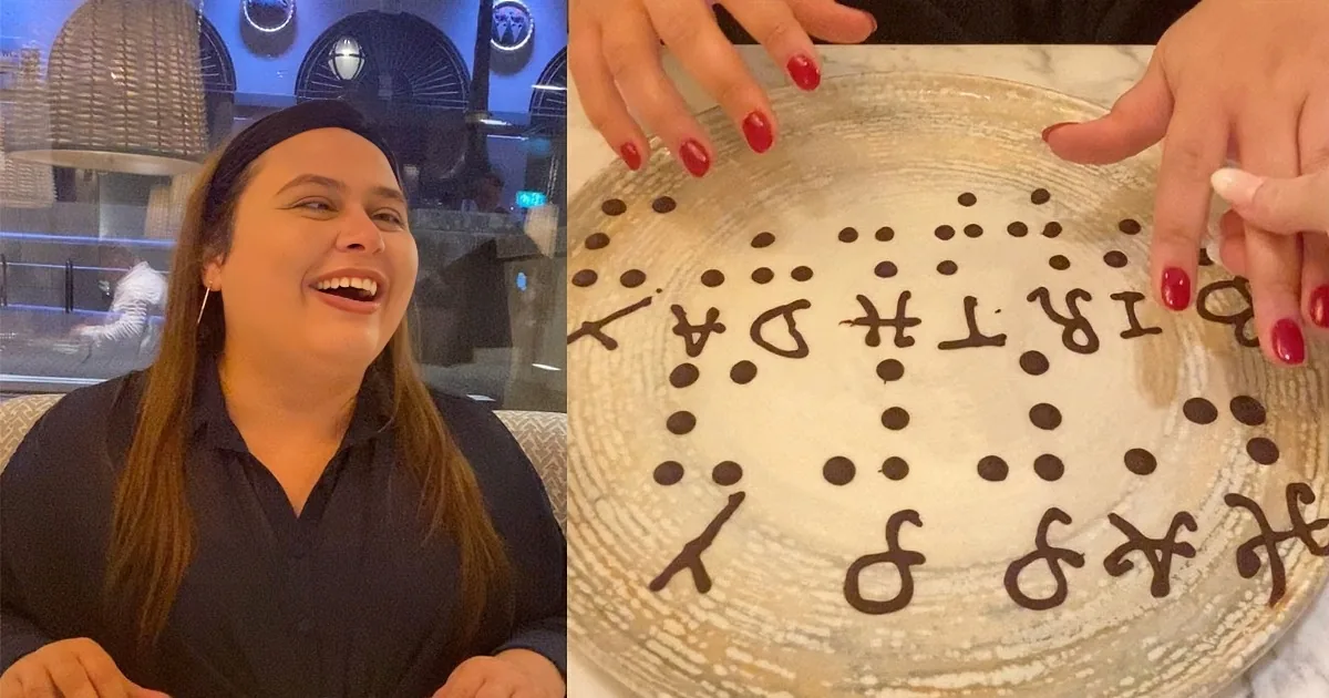A woman laughs while holding a plate with Braille letters on it, showcasing a unique way to communicate.