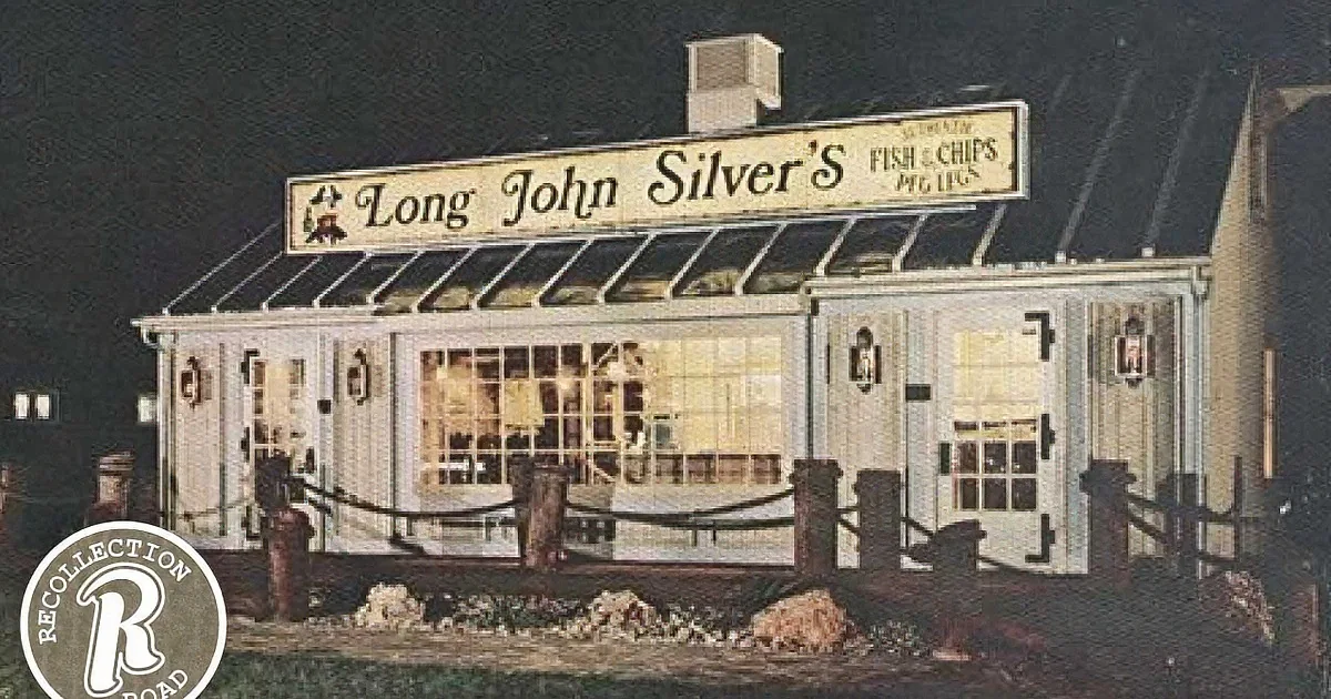 A Long John Silver's restaurant is illuminated at night, featuring a sign and a glass awning.