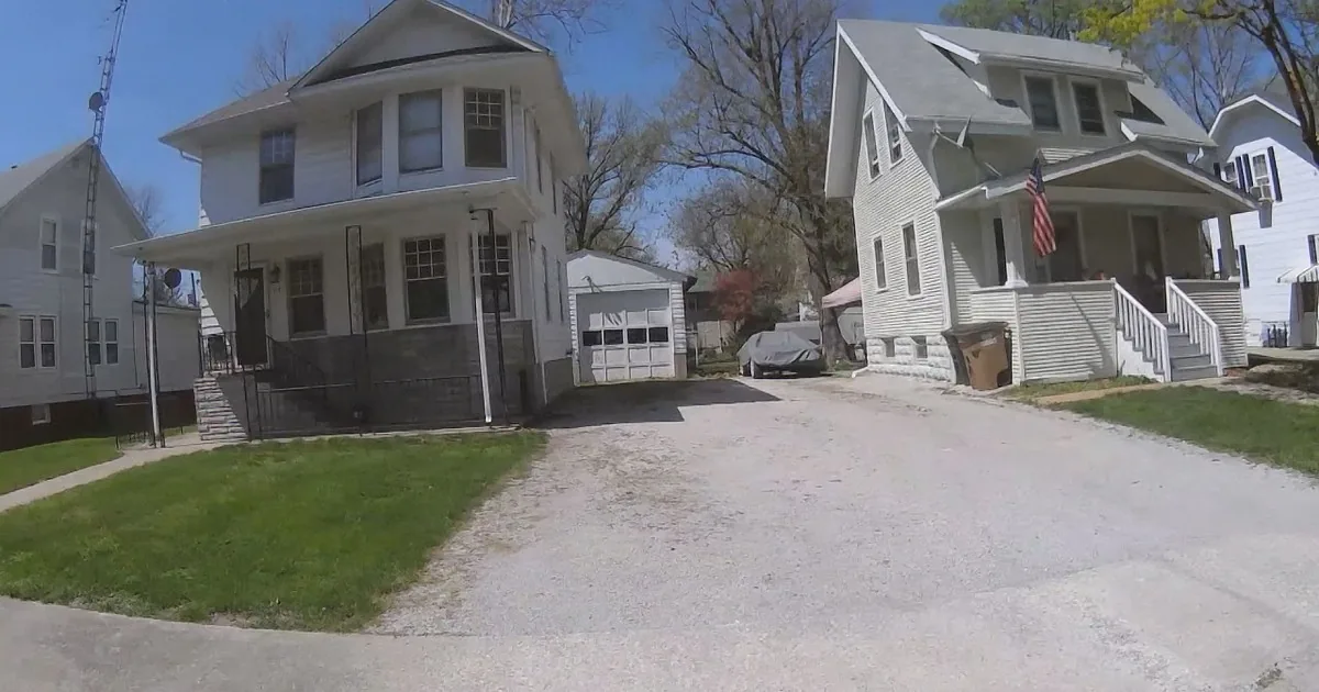 A white two-story house with a porch and a parked black SUV in front.