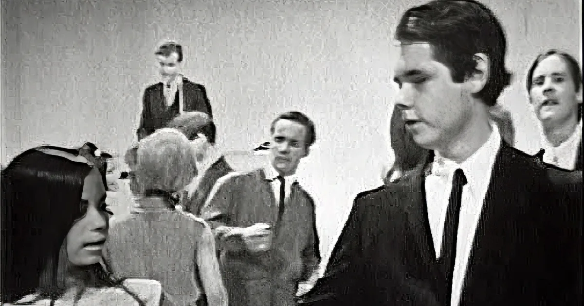 A man in a suit and a woman in a white dress are dancing in a crowded room.