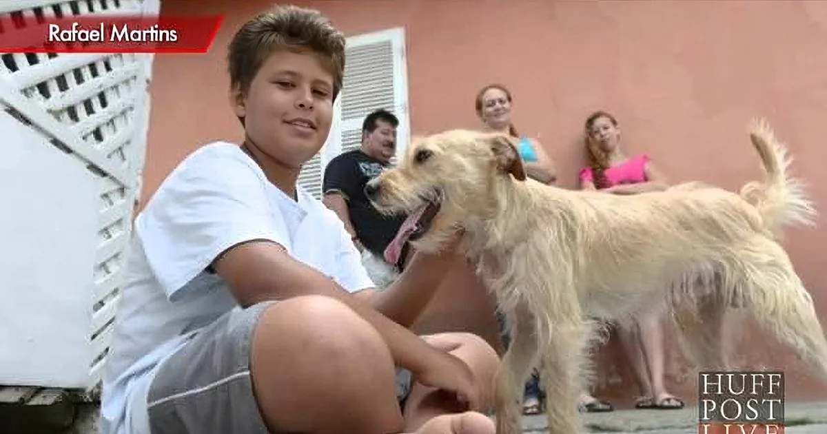 A person in black and white tracksuit pets a light-colored dog on a paved surface.