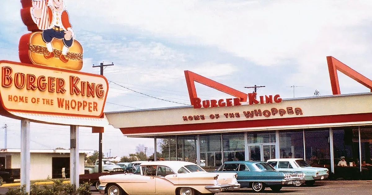 A Burger King sign featuring a king character and a child eating a Whopper with a crown on.