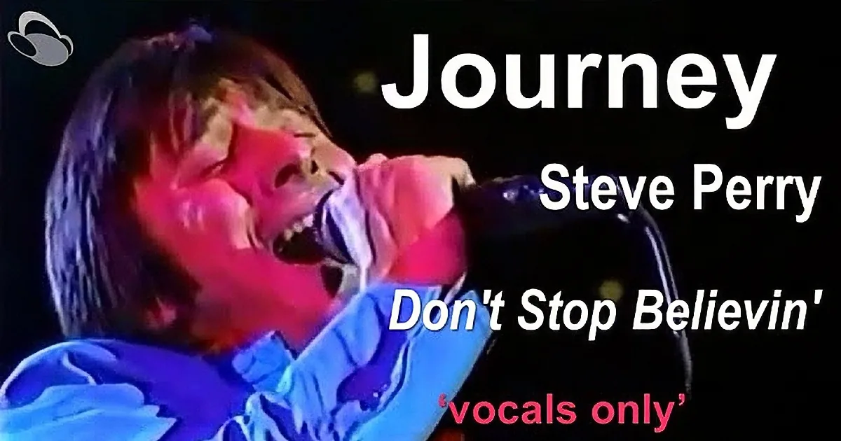 A person in a blue shirt is passionately singing into a microphone with a red light illuminating their face.