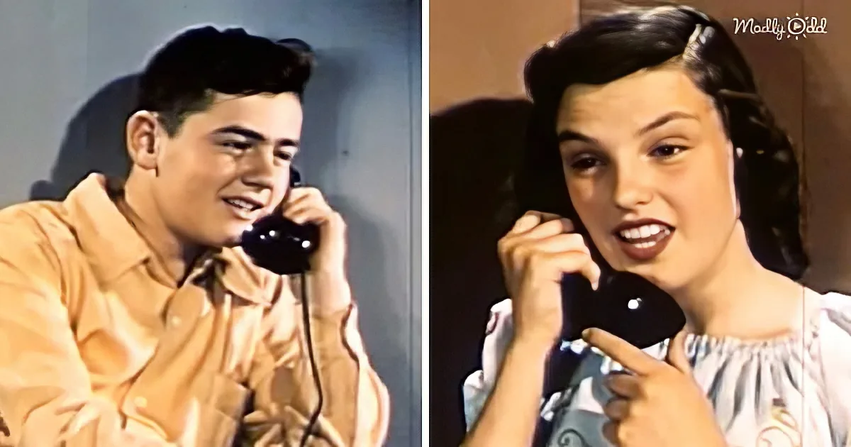 A man and a woman are smiling while holding black rotary phones, suggesting a nostalgic or vintage setting.