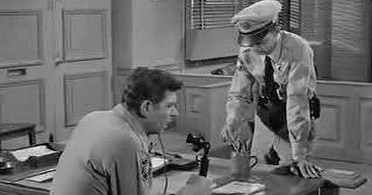 A man in a sheriff's uniform adjusts another man's tie while a third man in a cap looks on.