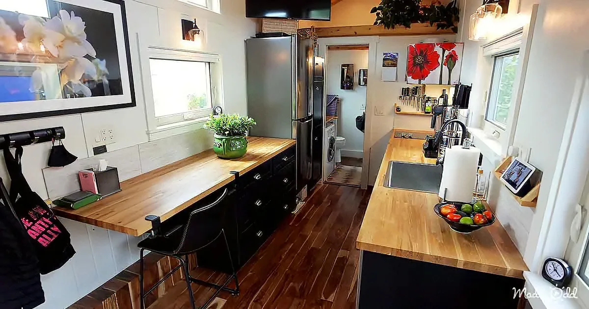 A cozy kitchen with wooden countertops, black cabinets, and a bowl of fresh produce on the counter.