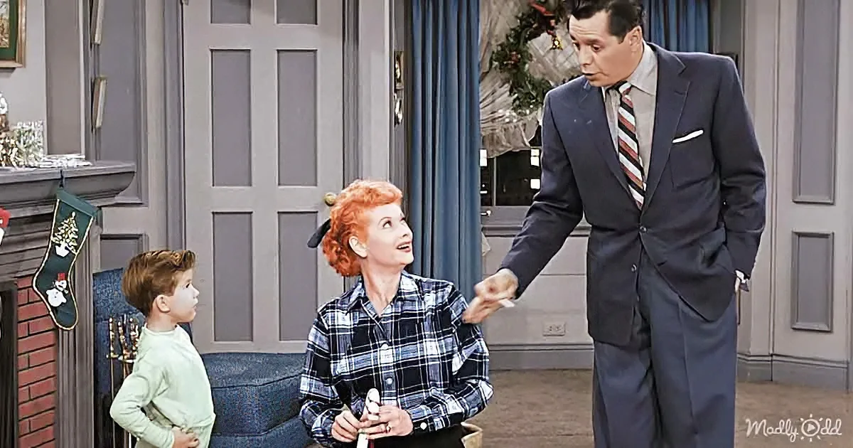 A woman in a plaid shirt is holding a small object, looking up at a man in a suit who is extending his hand towards her.