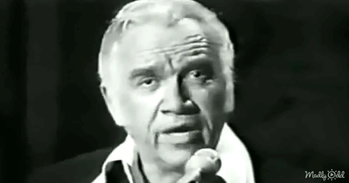 An older man with a microphone, wearing a white shirt, appears to be speaking or singing.