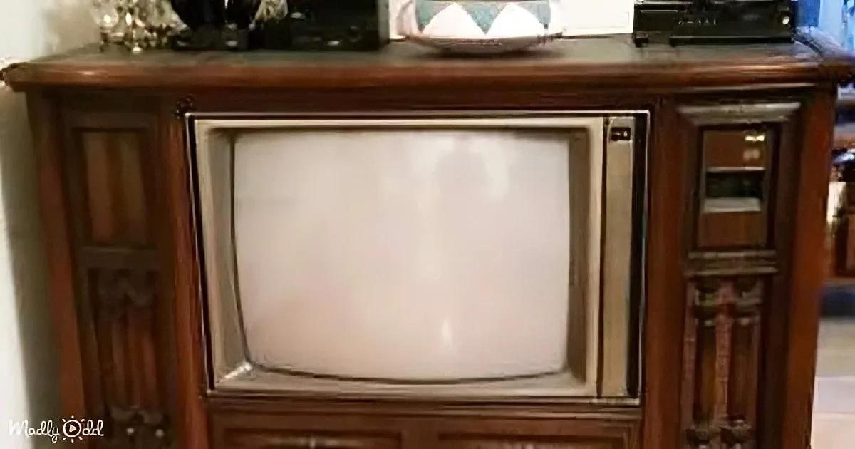 An old wooden TV cabinet with a vintage tube TV inside, surrounded by decorative items on top.
