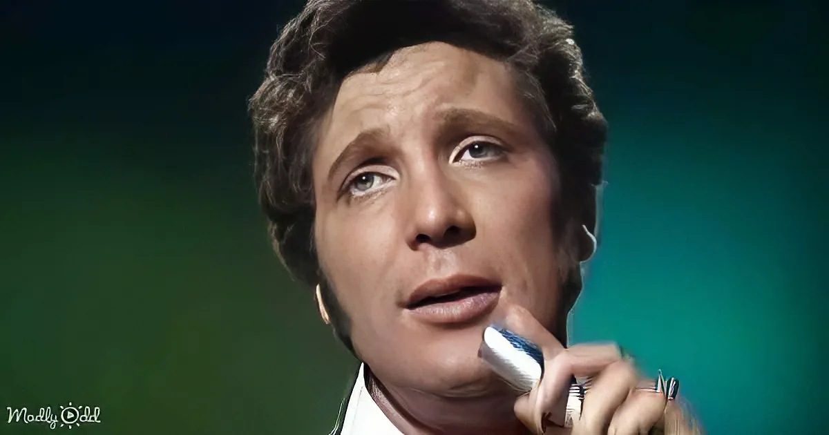 A man with short, dark hair holding a toothbrush near his mouth, looking upwards.